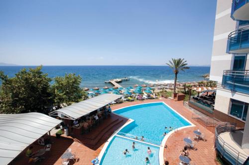 una piscina junto a un hotel y el océano en Faustina Hotel & Spa, en Güzelçamlı