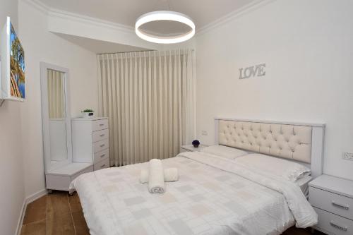 a white bedroom with a large white bed and a mirror at Boutique Lake Kinneret Apartment in Tiberias
