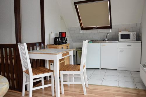 uma cozinha com uma mesa, 2 cadeiras e um micro-ondas em Pension Heister em Isselburg