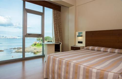 a hotel room with a bed and a large window at Hotel Portocobo in Santa Cruz de Oleiros