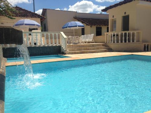 a swimming pool with a fountain in front of a house at Hotel Real São Lourenço in São Lourenço