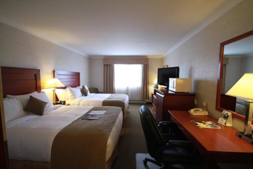 a hotel room with two beds and a desk at Best Western Gold Rush Inn in Whitehorse