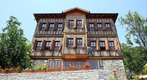 un grand bâtiment avec des fenêtres au-dessus d'un mur en pierre dans l'établissement Dadibra Konak Hotel, à Safranbolu