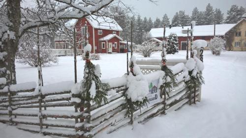 a fence covered in snow in front of a house at Näsets Marcusgård in Furudal