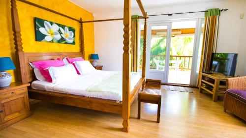 a bedroom with a four poster bed with pink pillows at Pingo Studio in Le Morne