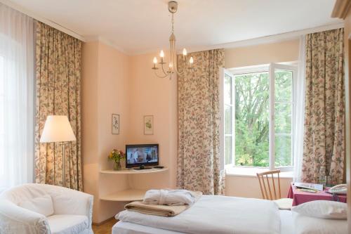 a bedroom with a bed and a chair and a window at Hotel Landsitz Pichlschloss in Neumarkt in Steiermark