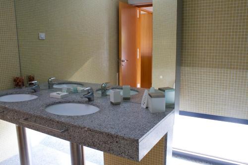 a bathroom with three sinks and a large mirror at Design House Aroeira Golf in Charneca