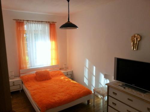 a bedroom with a bed with an orange blanket and a window at Privatzimmer Dimitrova in Ulrichsberg
