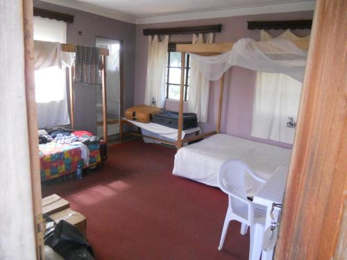 a bedroom with two bunk beds and a table and chairs at Masaka Backpackers, Tourists Cottage & Campsite in Masaka