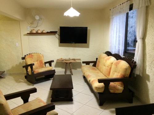 a living room with a couch and chairs and a tv at Casa Confortável - Cabo Frio in Cabo Frio