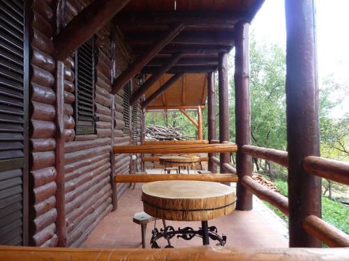a porch of a log cabin with a table and a stool at Etno domaćinstvo Milenković in Despotovac