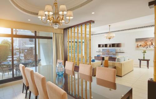 a dining room and living room with a glass table and chairs at Roda Beach Resort in Dubai