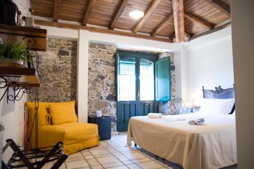 a bedroom with a bed and a yellow chair at Antico Borgo Etneo Agriturismo in Calatabiano