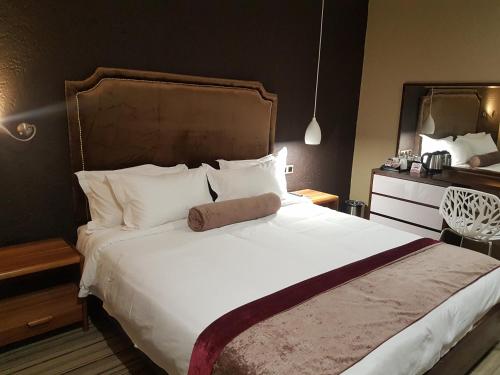 Un dormitorio con una cama grande con sábanas y almohadas blancas. en La Signature Guest house, en Francistown