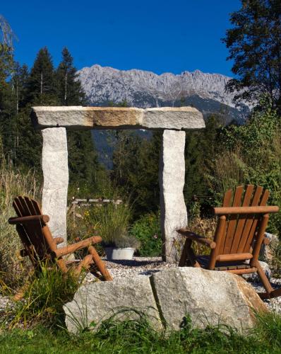 two chairs and a stone arch with mountains in the background at Pension Aloisia in Scheffau am Wilden Kaiser