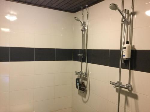 y baño con ducha y azulejos blancos y negros. en Majatalo Jurtta, en Rautuskylä