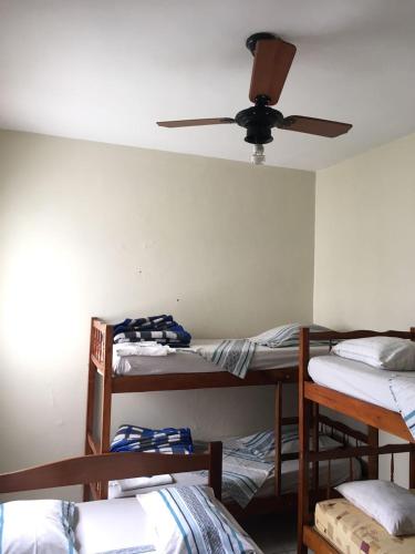 a room with three bunk beds and a ceiling fan at Hotel Santa Rita in Aparecida