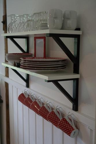 a shelf with plates and utensils on a wall at Ladugårdens Pub & Sal in Enhörna