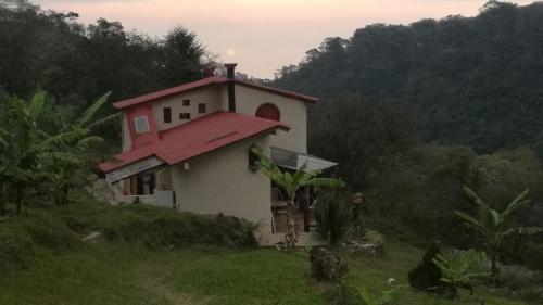 una pequeña casa con techo rojo en una colina en Casa de campo vacacional "Tres Soles" en Xico, Veracruz en Xico