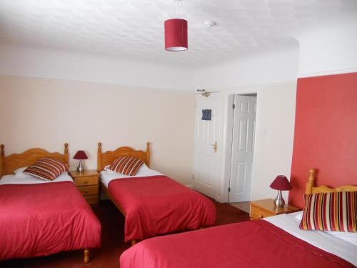 2 Betten in einem rot-weißen Zimmer in der Unterkunft Gateway Lodge in Speke