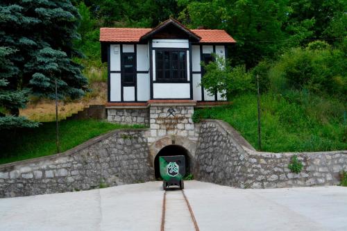 a small house with a green sign in front of a tunnel at Etno domaćinstvo Milenković in Despotovac