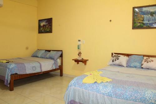 two beds in a room with yellow walls at Hotel LOL-HA in Cobá