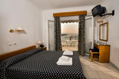 a bedroom with a bed and a television and a balcony at Lazaridis Luxury Studios & Apartments in Nea Roda