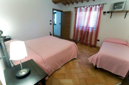 a bedroom with two beds and a table with a lamp at Villa Martina in Fermignano