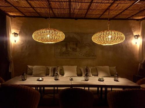 a dining room with a table and chandeliers at Dar Alya Essaouira Maison et table d'hôtes in Ghazoua