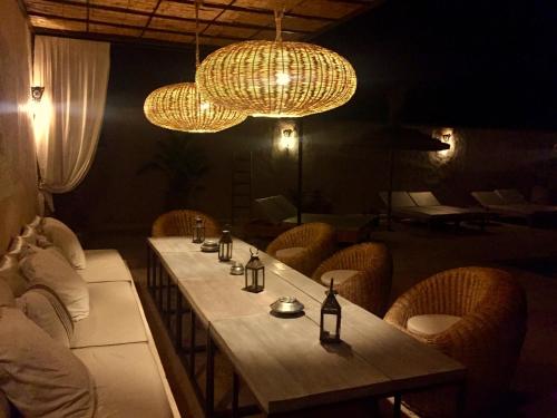 a dining room with a long table and chandeliers at Dar Alya Essaouira Maison et table d'hôtes in Ghazoua