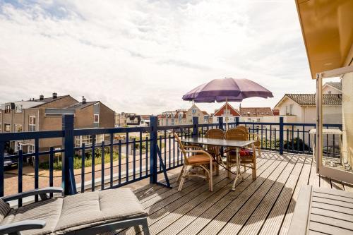 a balcony with a table and chairs and an umbrella at Appartementen de Strandloper in Bergen aan Zee