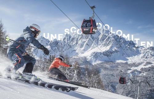 two people skiing down a snow covered mountain with a ski lift at Cafe Pension Erbhof in Kartitsch
