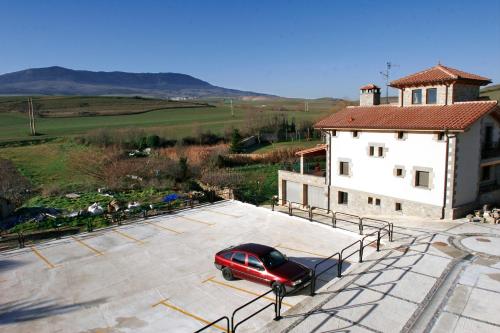 a red car parked in a parking lot next to a building at Hotel Agorreta in Salinas de Pamplona
