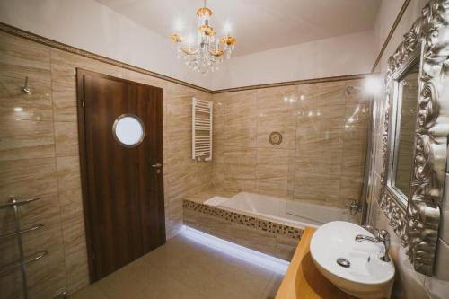 a bathroom with a sink and a bath tub and a chandelier at Apartamenty Blisko Centrum in Toruń
