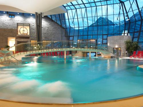a large swimming pool in a building with a bridge at Haus Alp Deluxe in Längenfeld