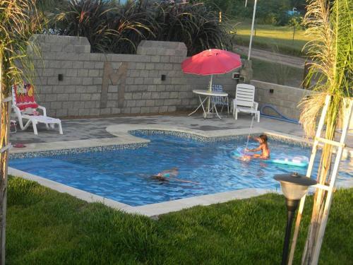two people swimming in a pool with a red umbrella at HM San Jose in San José