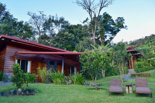 a house with two chairs in the yard at Arco Iris Lodge in Monteverde Costa Rica
