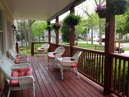 a porch with chairs and tables and flowers on it at Ahoy Inn Guesthouse in Put-in-Bay