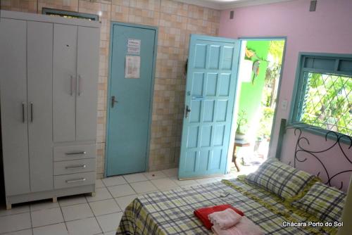 um quarto com portas azuis e uma cama com um cobertor em Pousada Chácara Porto do Sol em Jacumã