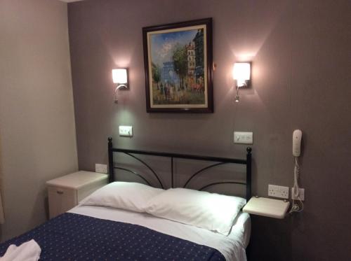 a bedroom with a bed and a phone on the wall at Central Hotel in London