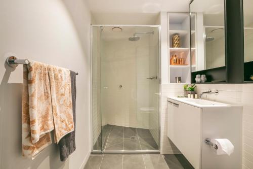uma casa de banho com uma cabina de duche em vidro e um lavatório. em Quest Flemington Central em Melbourne