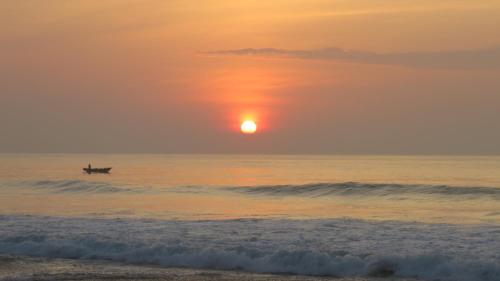 a person in a boat in the ocean at sunset at The Long Hostel in Arugam Bay