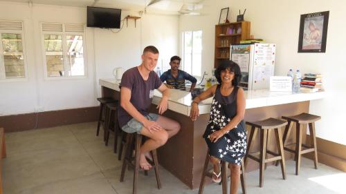 a group of people sitting at a counter in a kitchen at The Long Hostel in Arugam Bay