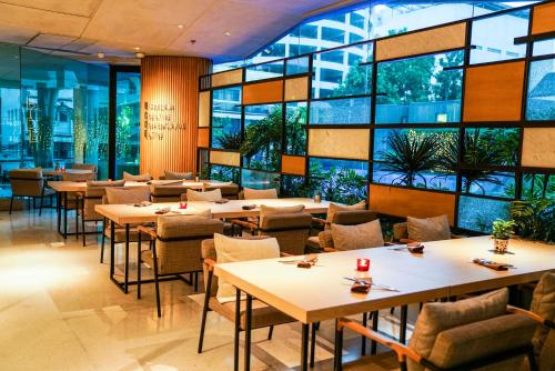 a restaurant with tables and chairs and windows at LiT BANGKOK Hotel in Bangkok
