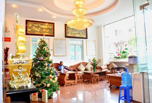 a christmas tree in a living room with a woman at A25 Hotel -137 Nguyễn Du - Đà Nẵng in Danang