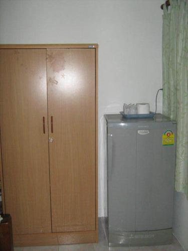 a refrigerator next to a wooden cabinet in a room at Lamoon Lamai Residence & Guesthouse in Lamai