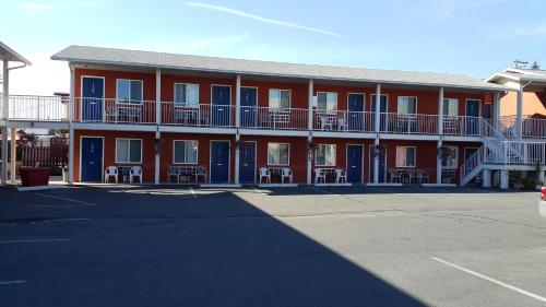 a large red building with blue doors and a parking lot at Cactus Tree Inn in Oliver