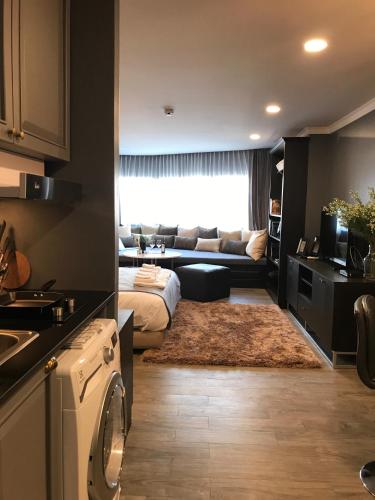 a living room with a couch and a kitchen at Stay in Style at Nimman R306B in Chiang Mai