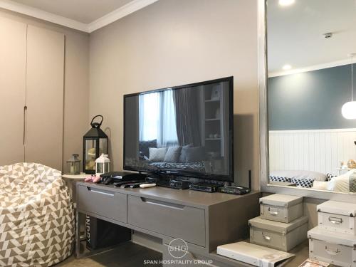a living room with a large television on a dresser at Stay in Style at Nimman R201 in Chiang Mai