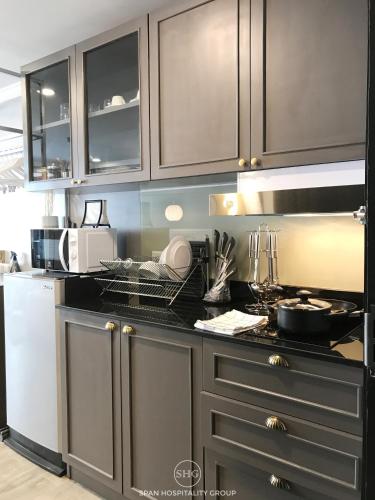 a kitchen with brown cabinets and a black counter top at Stay in Style at Nimman R201 in Chiang Mai